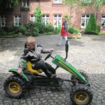 Leon fährt mit dem Traktor über den Hof.  (vergrößerte Bildansicht wird geöffnet)